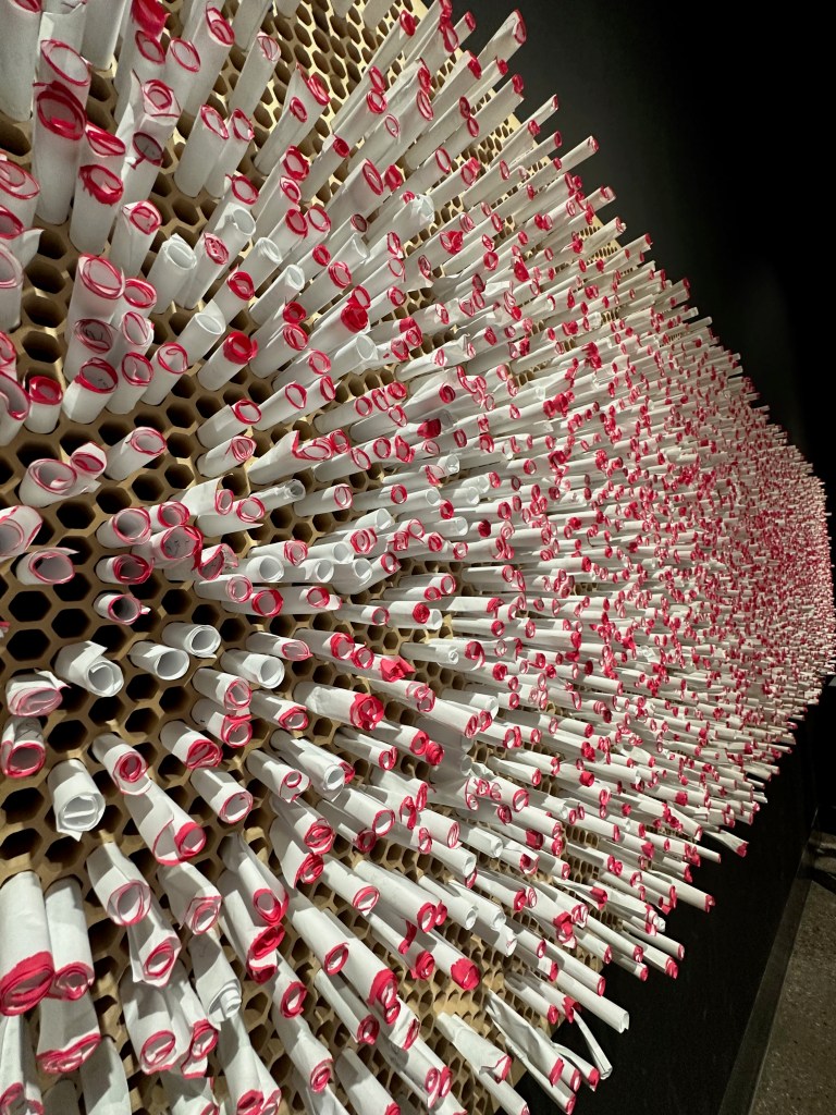 An interactive honeycomb wall lets visitors exchange anonymous, pink-edged notes filled with thoughts and kindness.